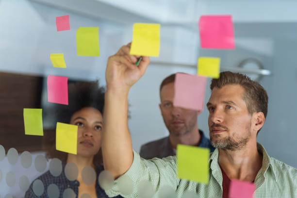 istock Coworkers discussing new ideas on a glass wall 1128214882