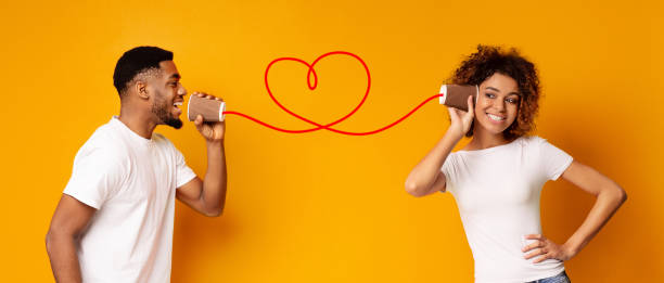 istock Young black couple with can phone on orange background 1128216167
