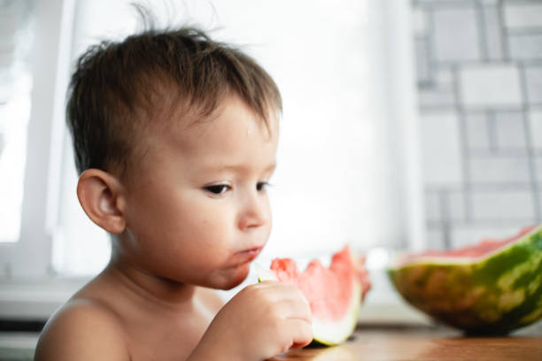 istock Cute little boy eating watermelon in the kitchen 1128216962