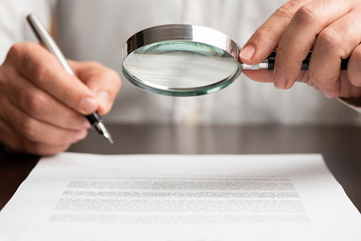 Businessman Reading Contract Carefully Using Magnifying Glass Before Signing