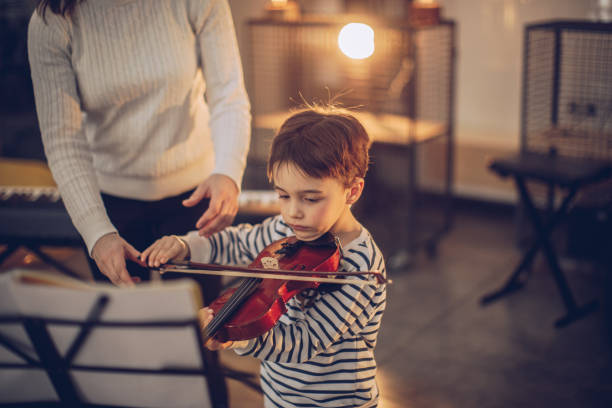 istock Little boy playing violin in music school 1128218897