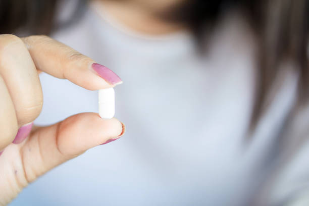 istock closeup woman hand holding one antibiotic pill 1128219771