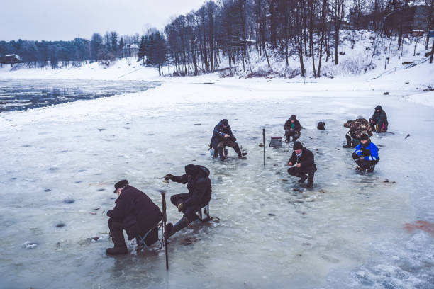 Fishing on ice Lots of fisherman fishing on watery ice. Overcast day, blueish colour mood. man ice fishing stock pictures, royalty-free photos & images
