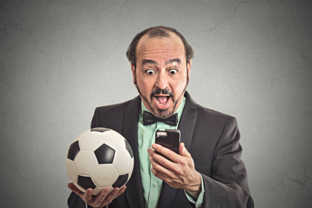 スマート フォン見てゲーム サッカーを保持にショックを受けて興奮して男 - business team corporate business business person ストックフォトと画像