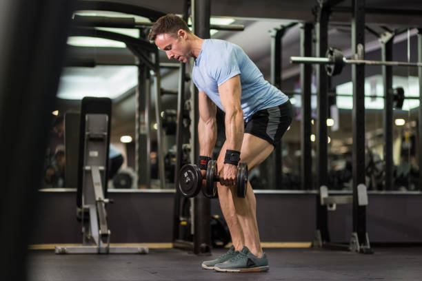 istock Muscular man pulling heavy dumbbell at the gym. 1128221013