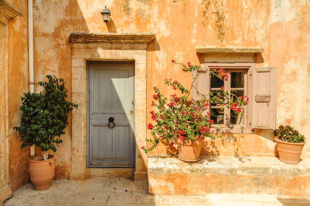 Yellow wall of the monastery with doors, window and flowerpots