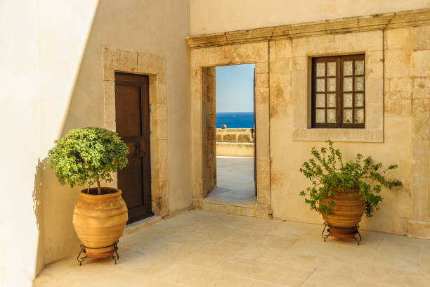 parete gialla del monastero con porte, finestre e vasi da fiori - greek islands table window sun foto e immagini stock