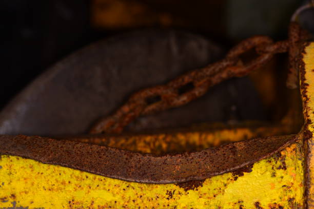 istock Rusty chain behind bent component on  worn yellow agricultural plow 1128227360
