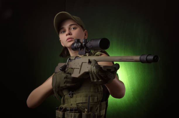 ヘイズの暗い背�景の上に手で銃を持つポーズ軍の特別な服の女の子 - military uniform ストックフォトと画像