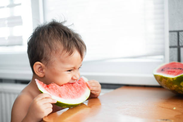 istock Cute little boy eating watermelon in the kitchen 1128229447