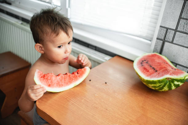 istock Cute little boy eating watermelon in the kitchen 1128229691