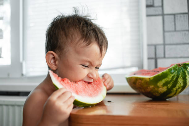 istock Cute little boy eating watermelon in the kitchen 1128230047
