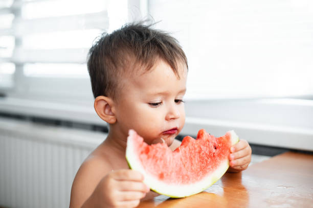 istock Cute little boy eating watermelon in the kitchen 1128230742