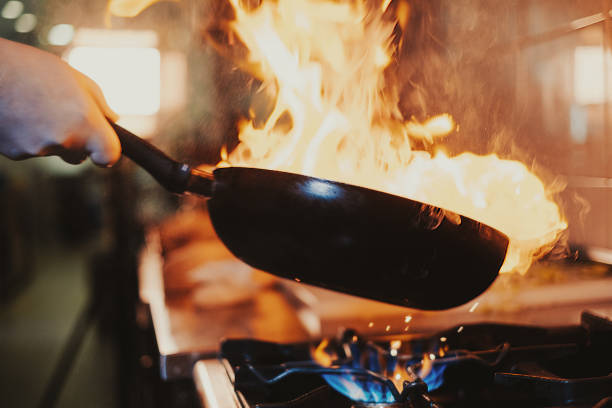 Chef steering flamed frying pan stock photo