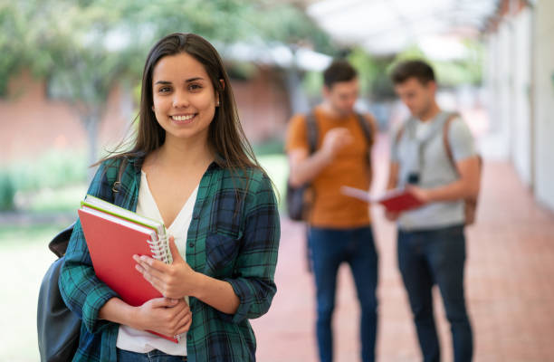 istock Beautiful young university student holding her notebooks while facing camera with a toothy smile 1128235717