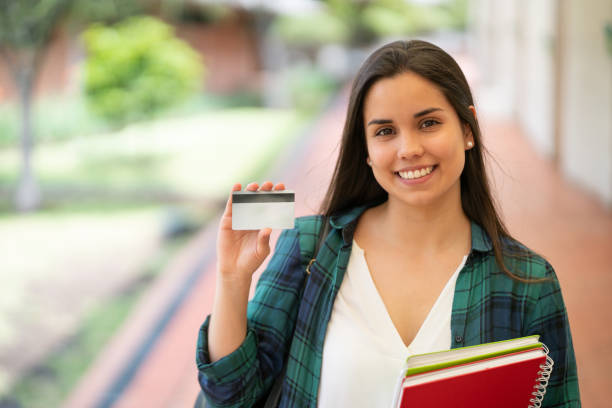 istock Portrait of pretty young student holding a card to edit while facing camera smiling 1128235728