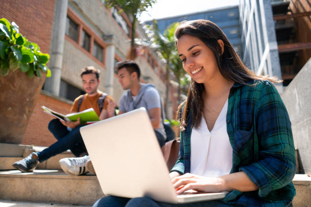 istock Female young student working on her laptop sitting around the college campus 1128235744