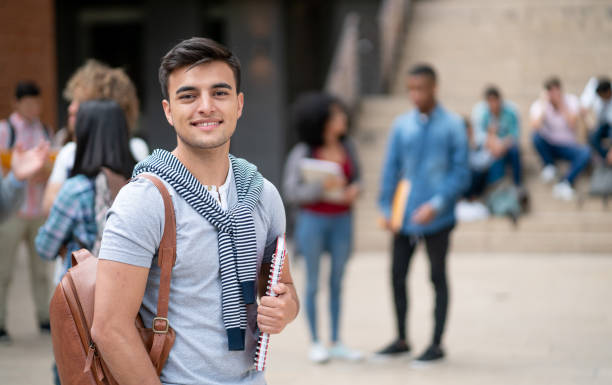 istock Portrait of confident young college student facing camera smiling while holding his notebooks 1128235775