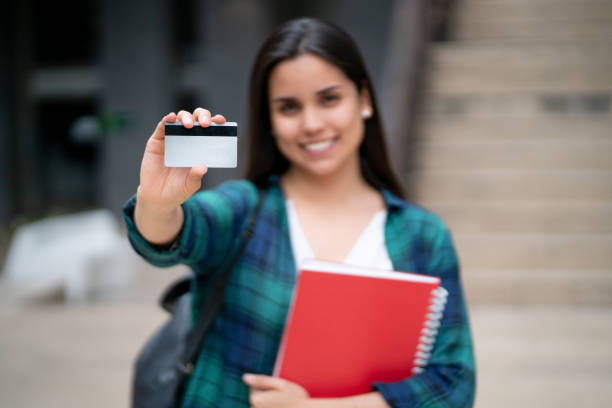 istock Beautiful young female student holding a card to edit uo front smiling at camera 1128235792