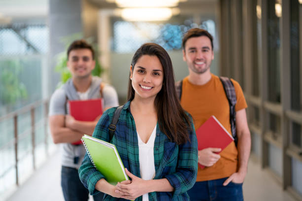 istock Group of students smiling at camera and female student standing at foreground 1128235806