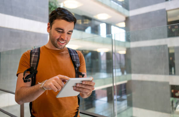 istock Young male college student in a building using his tablet while smiling 1128235815