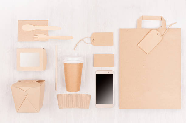 istock Blank different cardboard packaging for fast food - coffee cup, screen phone, cutlery, sugar, spice, container and box for sushi, noodles on white wood board. 1128236174