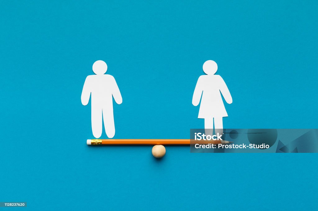 Drawn scales with words man and woman Gender equality in corporate world. Figures of man and woman on pencil seesaw, blue background, copy space Women Stock Photo