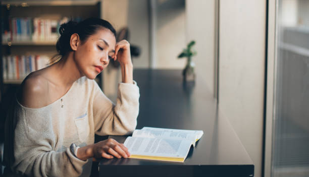 istock Beautiful young lady reading a book in library 1128238391