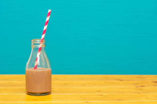 Young woman holding a delicious chocolate milkshake with candy toppings and a green straw, enjoying a sweet treat