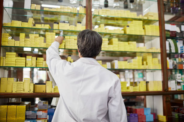 farmacêutico que procurara a medicina na prateleira na farmácia - rear view back men reaching - fotografias e filmes do acervo