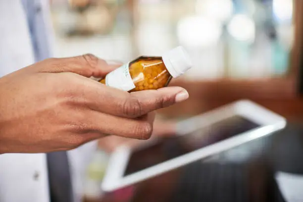 Close up pharmacist hands holding medicine bottle and digital tablet