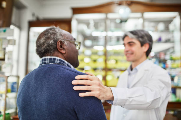 chimico sorridente consolante cliente anziano in farmacia - mano sulla spalla foto e immagini stock