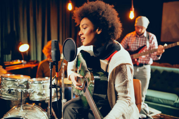 istock Mixed race woman singing and playing guitar. 1128240580