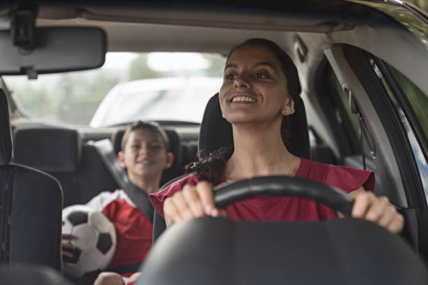 maman heureuse de soccer transportant des enfants à la pratique du football dans sa voiture - sentraîner photos et images de collection