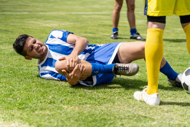 Soccer player on the floor after a foul Soccer player on the floor after a foul grabbing his leg in pain - sports concepts foul stock pictures, royalty-free photos & images