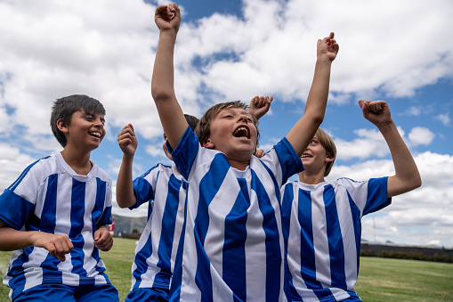 Excited group of young soccer players celebrating a goal on the field and looking very happy - competitive sports concepts