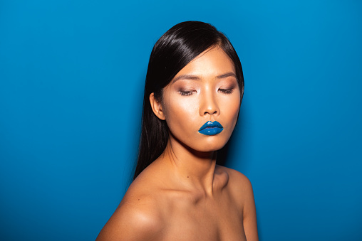 Asian female model posing in front of the blue background.