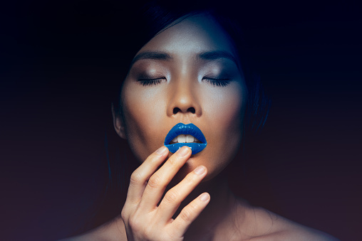 Asian female model posing in front of the blue background.