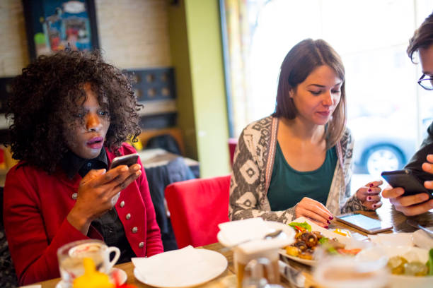 istock Friends use phone in restaurant 1128246039