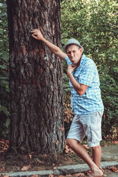 istock A man in a hat stands by a tree and shows his tongue. 1128246145
