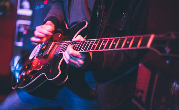 Electric guitar player on a stage Electric guitar player on a stage with colorful blue and purple scenic illumination blues guitar player stock pictures, royalty-free photos & images