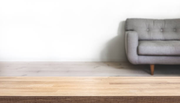istock Empty table top with simple home interior with grey couch blurred in the background. 1128247627