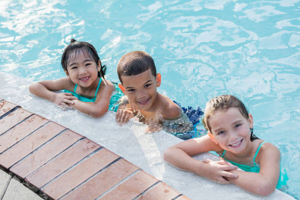 istock Three multi-ethnic children having fun in swimming pool 1128250101