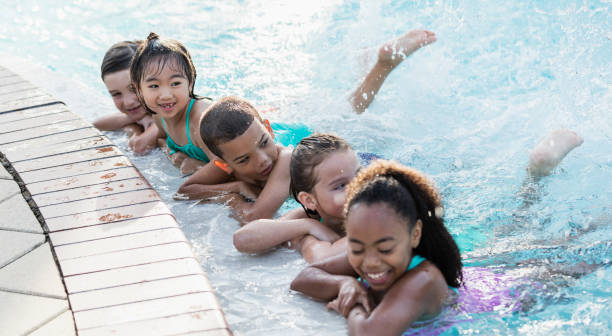 Children having fun kicking, splashing in swimming pool
