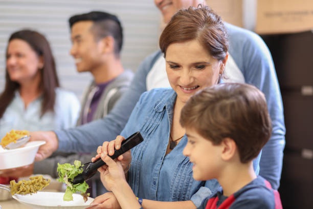 istock Multi-ethnic group of volunteers serves food at soup kitchen. 1128250813