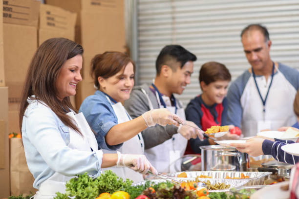 istock Multi-ethnic group of volunteers serves food at soup kitchen. 1128250934