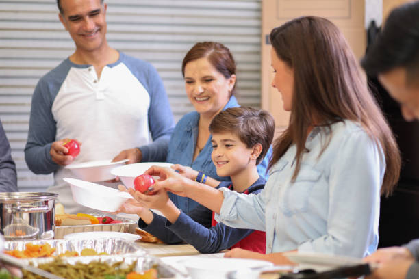 istock Multi-ethnic group of volunteers serves food at soup kitchen. 1128251122