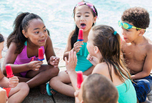 istock Multi-ethnic children at pool eating popsicles 1128252888
