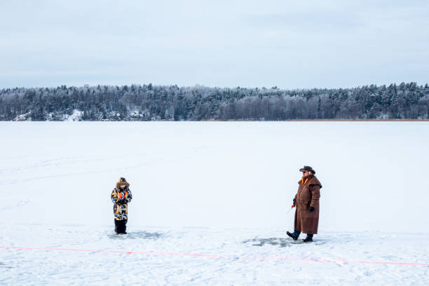vista del paisaje del invierno de un hombre y un niño en un lago congelado pesca del hielo. - sweden fishing child little boys fotografías e imágenes de stock