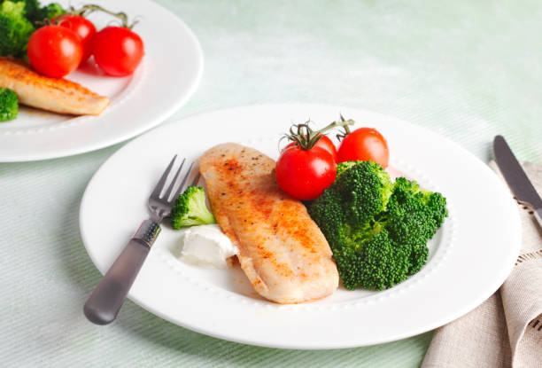 istock Fried Basa Fillet with sauce, broccoli and fresh tomato. 1128254925